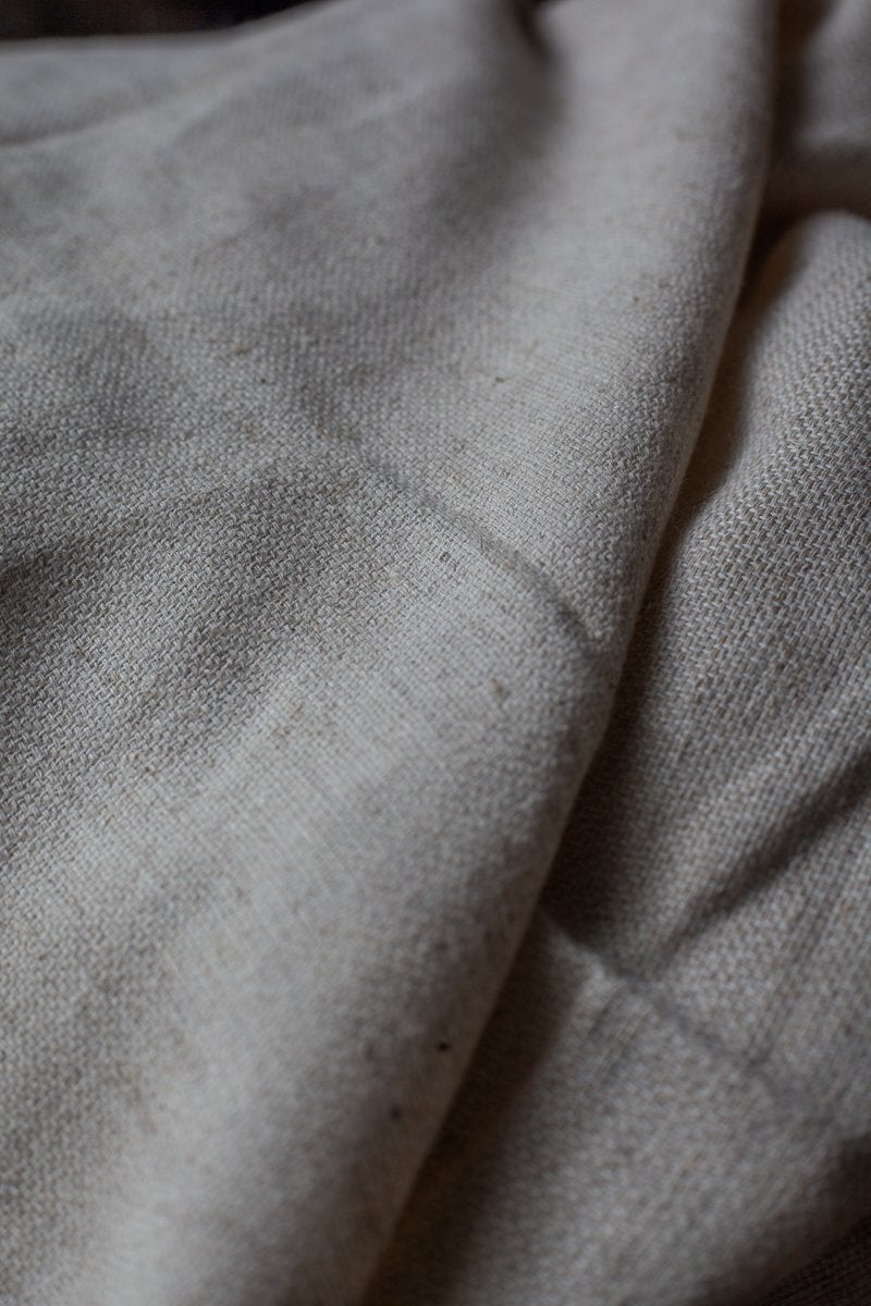 Close-up of undyed linen cotton fabric showing natural color variations and fiber texture