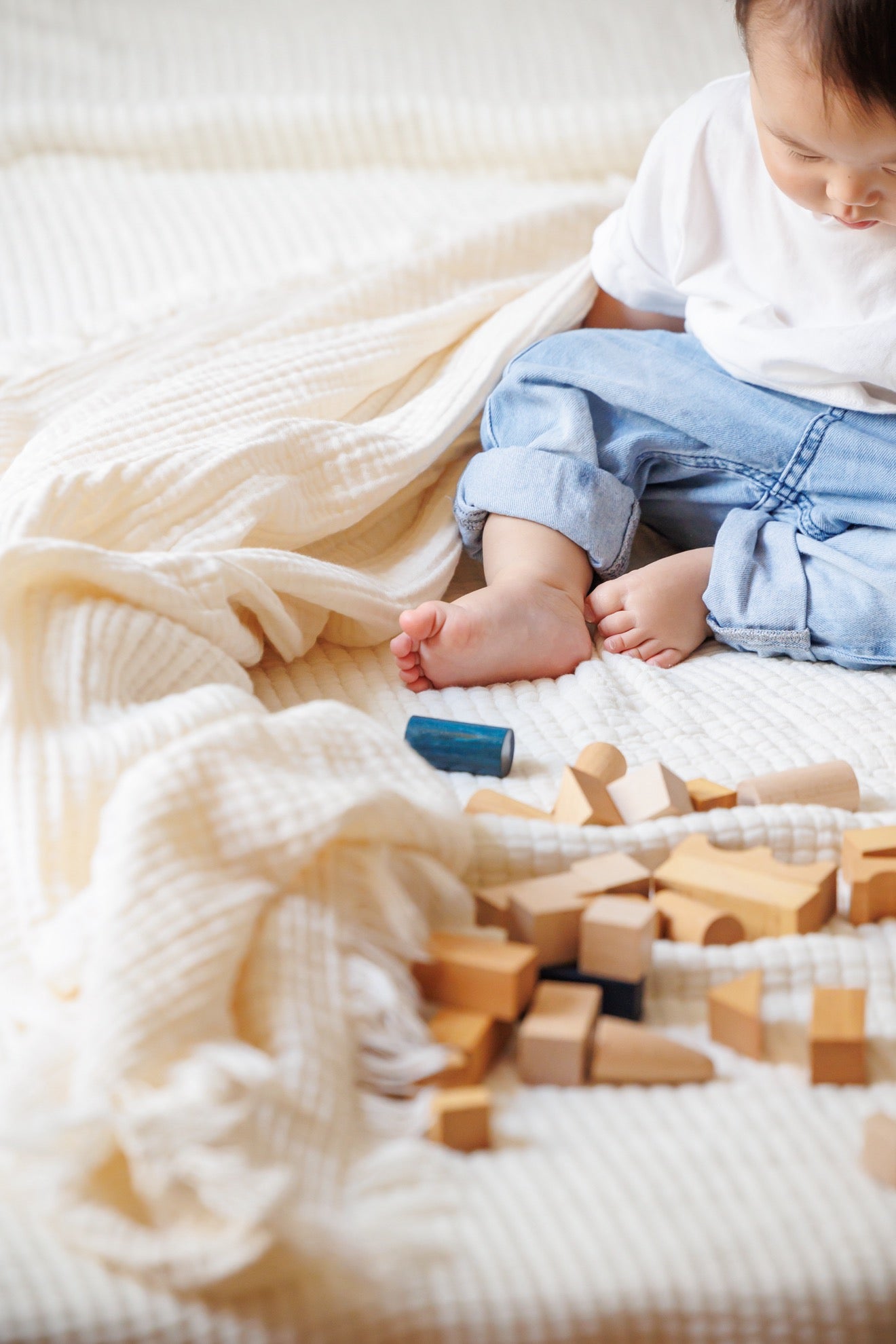 A baby playing with toys on the 8-layer crinkle gauze baby swaddle blanket, highlighting its versatile use.