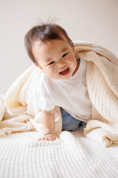 8-layer crinkle gauze baby swaddle blanket covering a child, showcasing its softness and comfort.