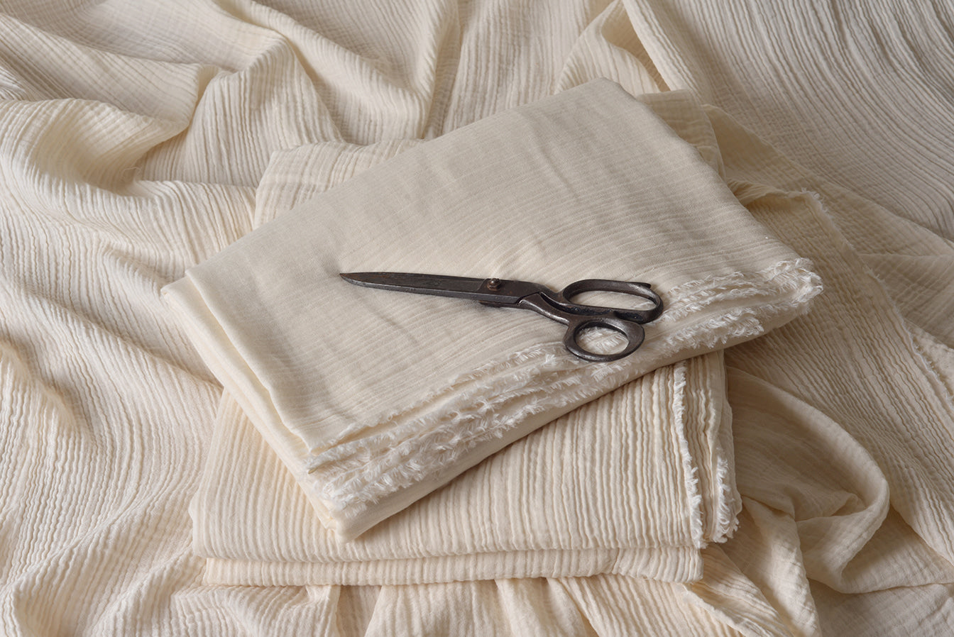 Folded double gauze muslin fabric showing soft crinkle texture and natural finish