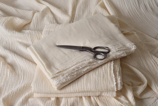 Folded double gauze muslin fabric showing soft crinkle texture and natural finish