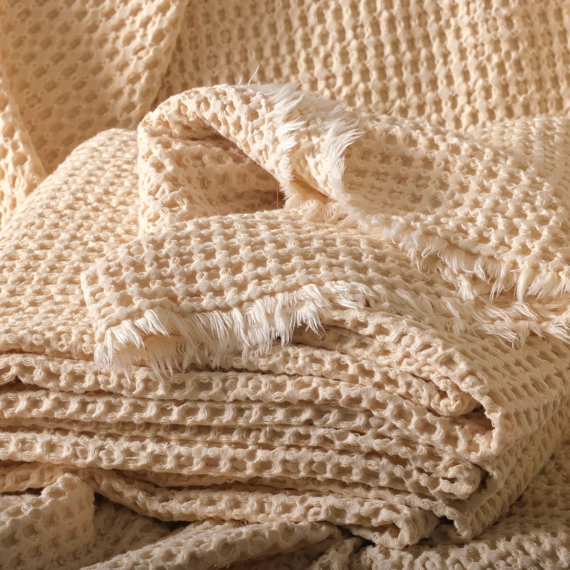 Undyed 100% cotton waffle fabric in natural color, stacked to show the soft honeycomb texture.