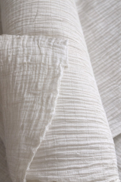 Close-up of undyed crinkle gauze cotton fabric showing vertical channel lines and natural texture, 61 in (155 cm) wide, dye-ready