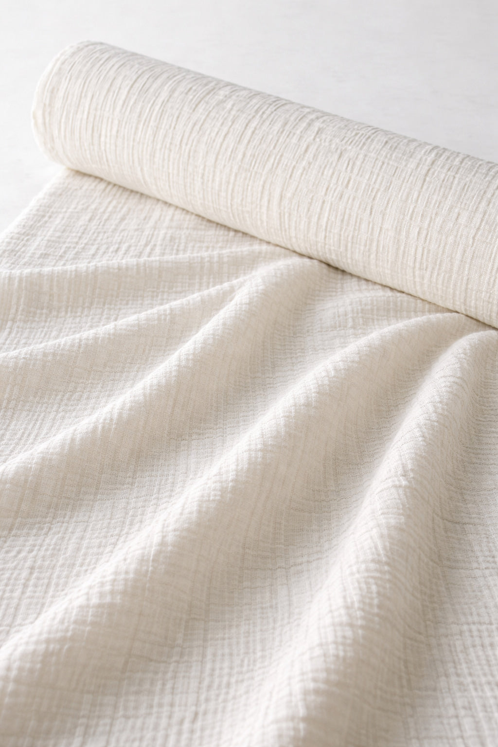 Undyed crinkle gauze cotton fabric on roll with draped yardage, 61 in (155 cm) wide, dye-ready for natural dyeing.