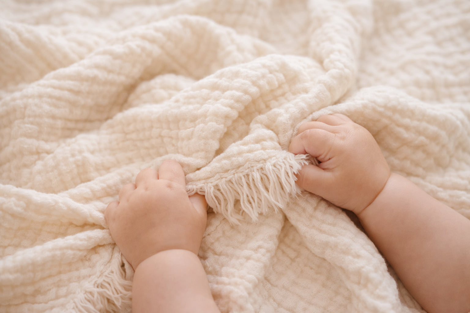 Close-up of the fringed edge and crinkled texture of our undyed 4-layer cotton muslin baby blanket, dye-ready.